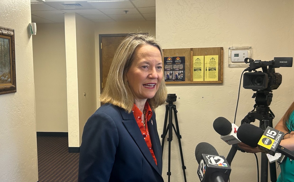 kris mayes speaks into microphones