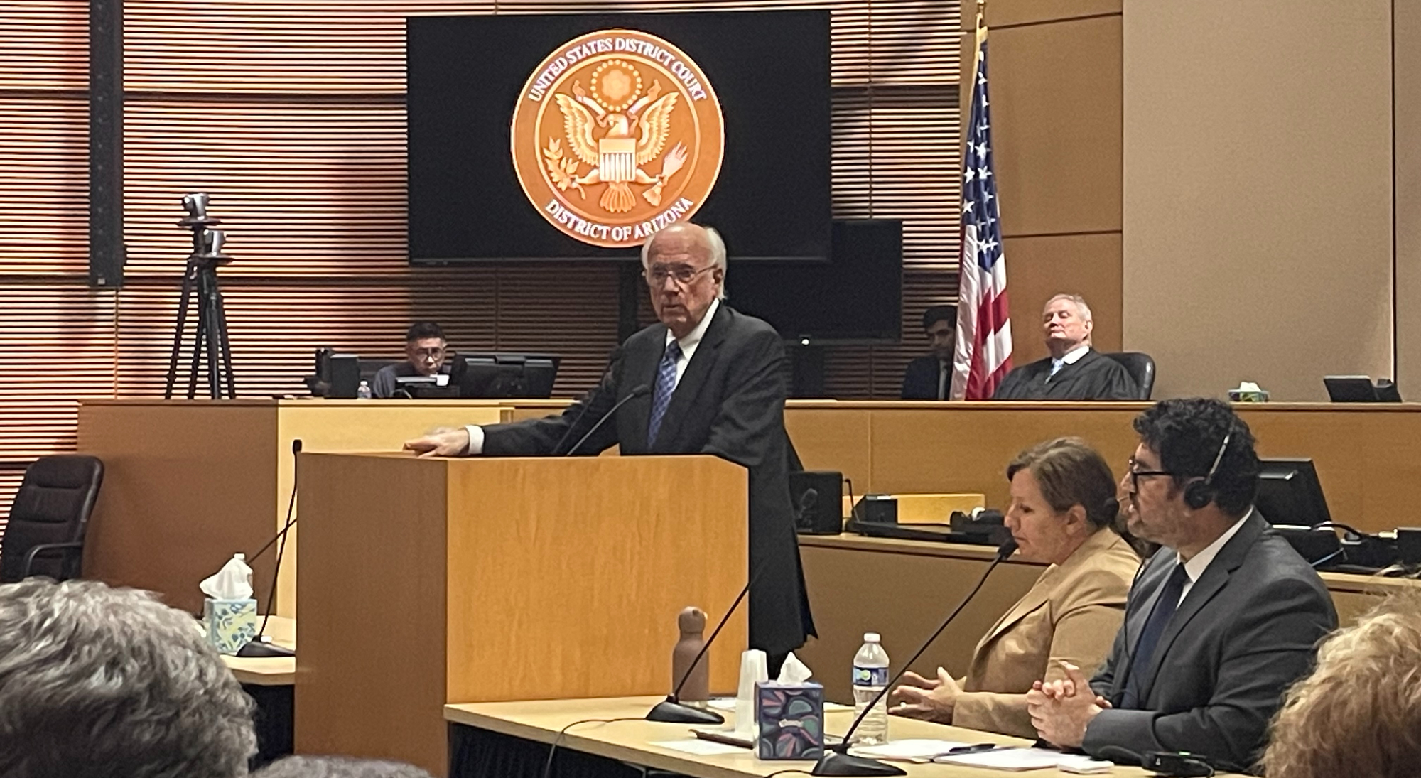 a man speaks at a podium in a courtroom