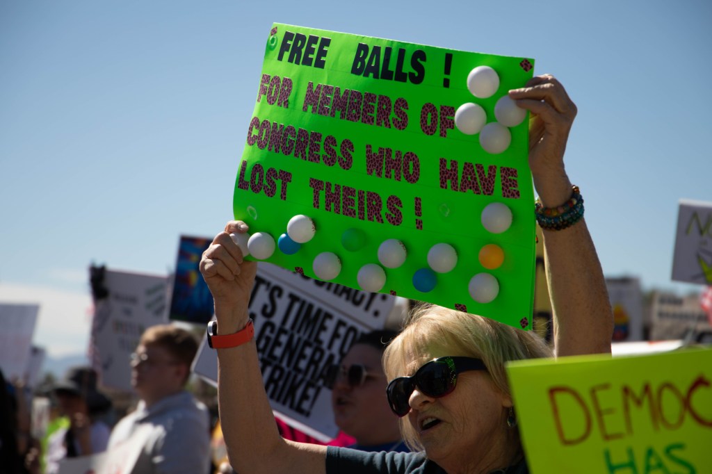 a protester holds a sign with ping pong balls attached, offering them to members of congress