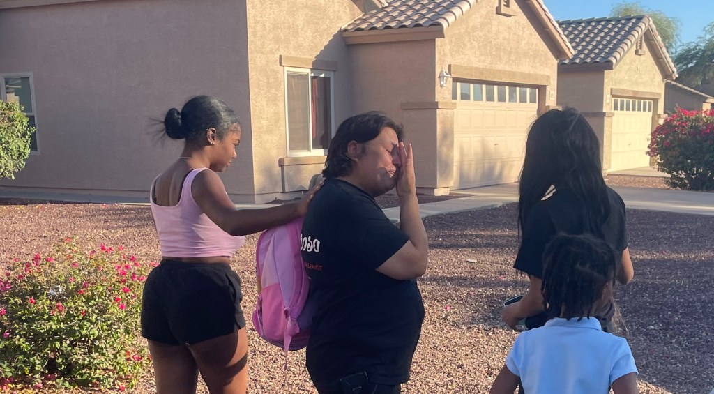 a woman cries while being comforted by others