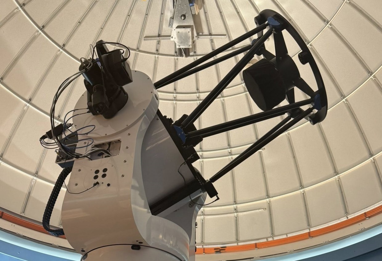 A large white telescope inside an observatory.