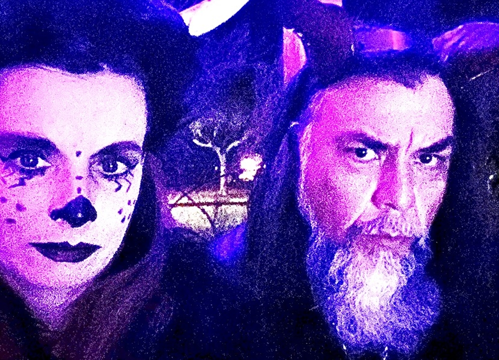 A woman in theatrical makeup next to a bearded man in devil horns.