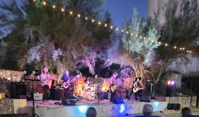A rock band performs on an outdoor stage.