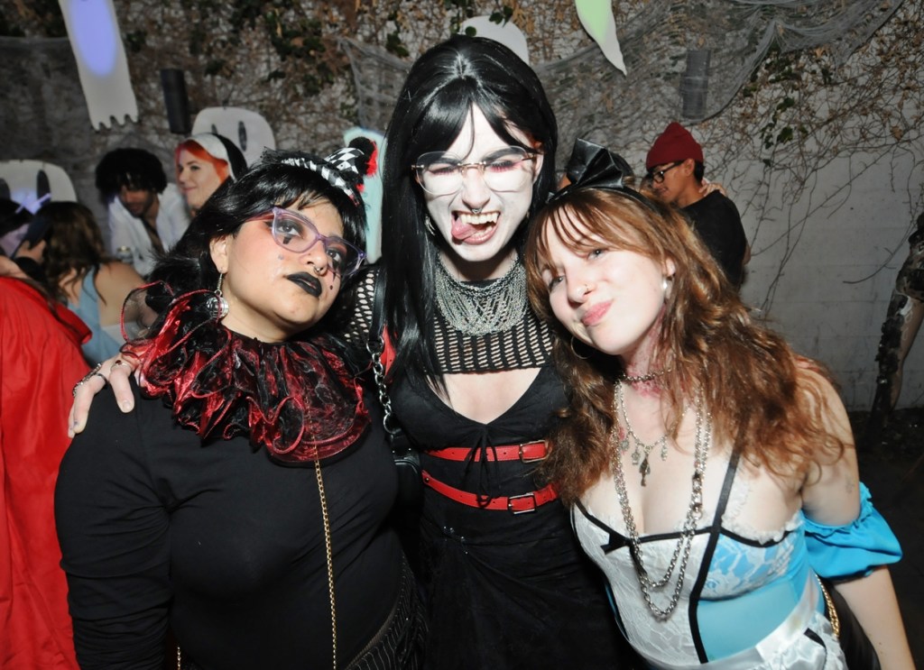 Three women in costume standing beside each other.