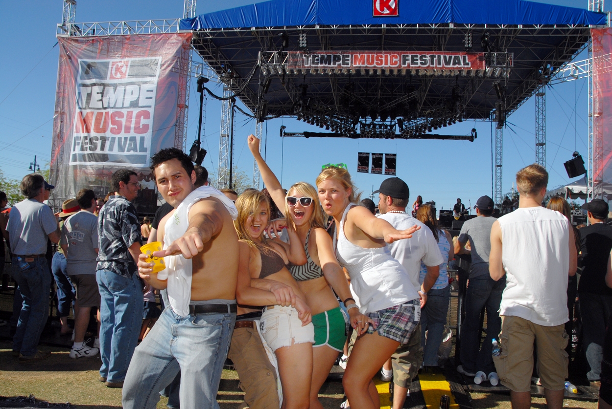 Four friends stand in front of a music festival stage.