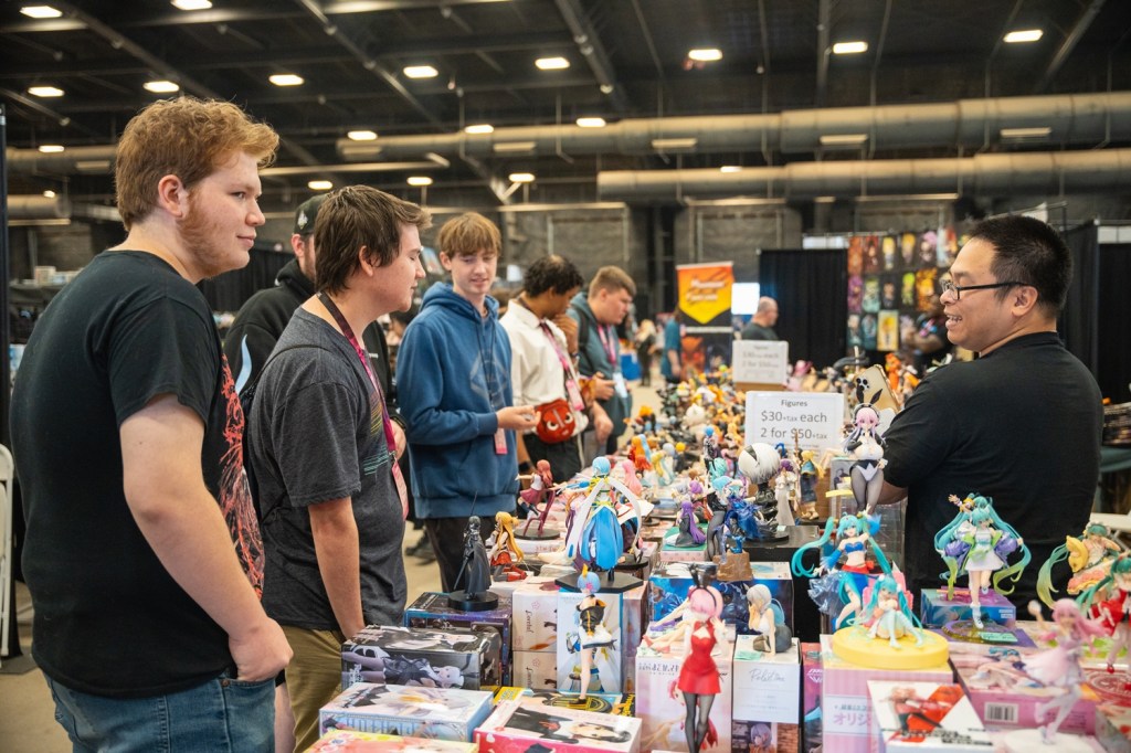 Attendees of an anime convention speak with a vendor.
