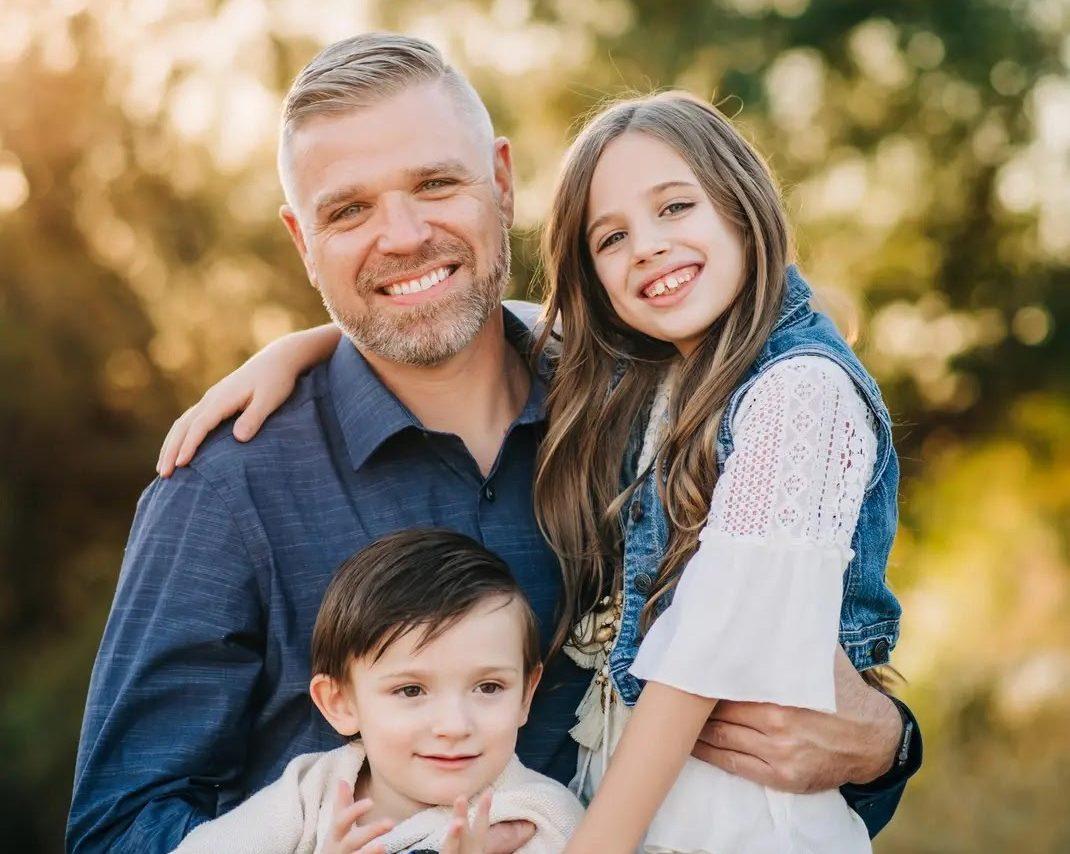 A man posing with his two children.