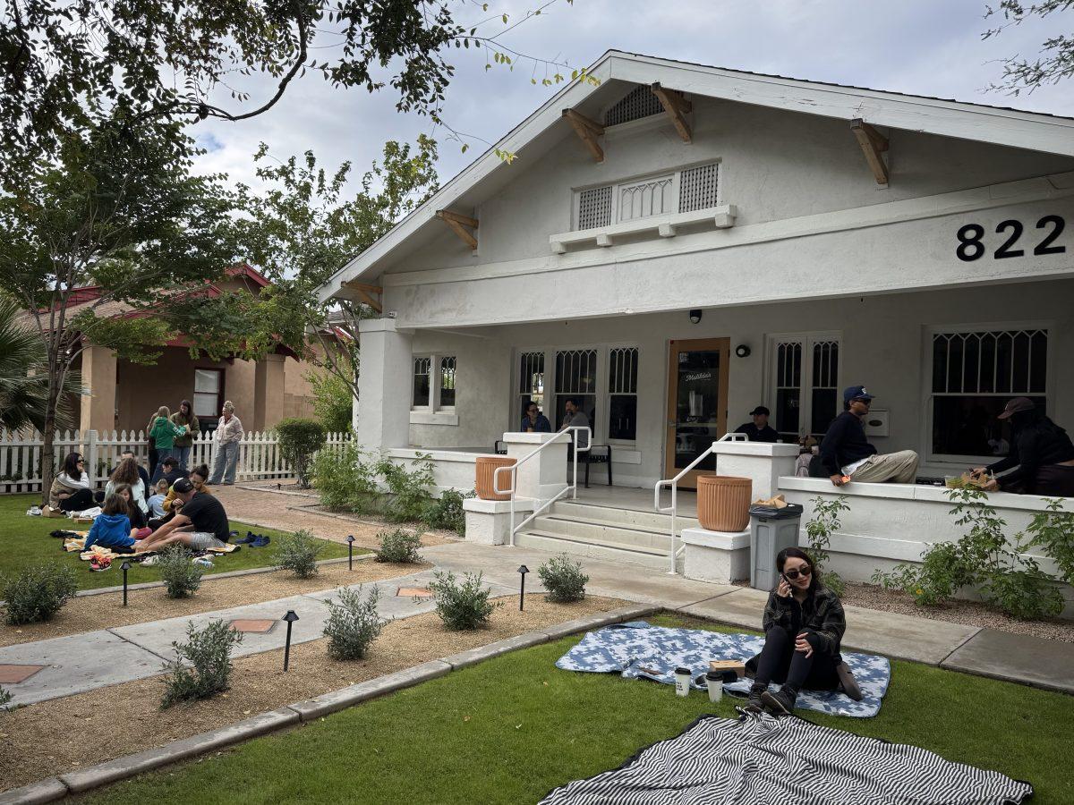 People lounging on a lawn of a bungalow house in Phoenix.