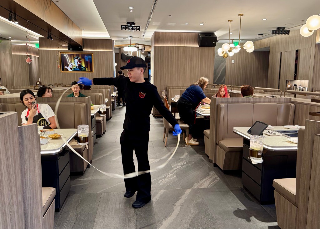 Man stretches noodles at a hot pot restaurant.