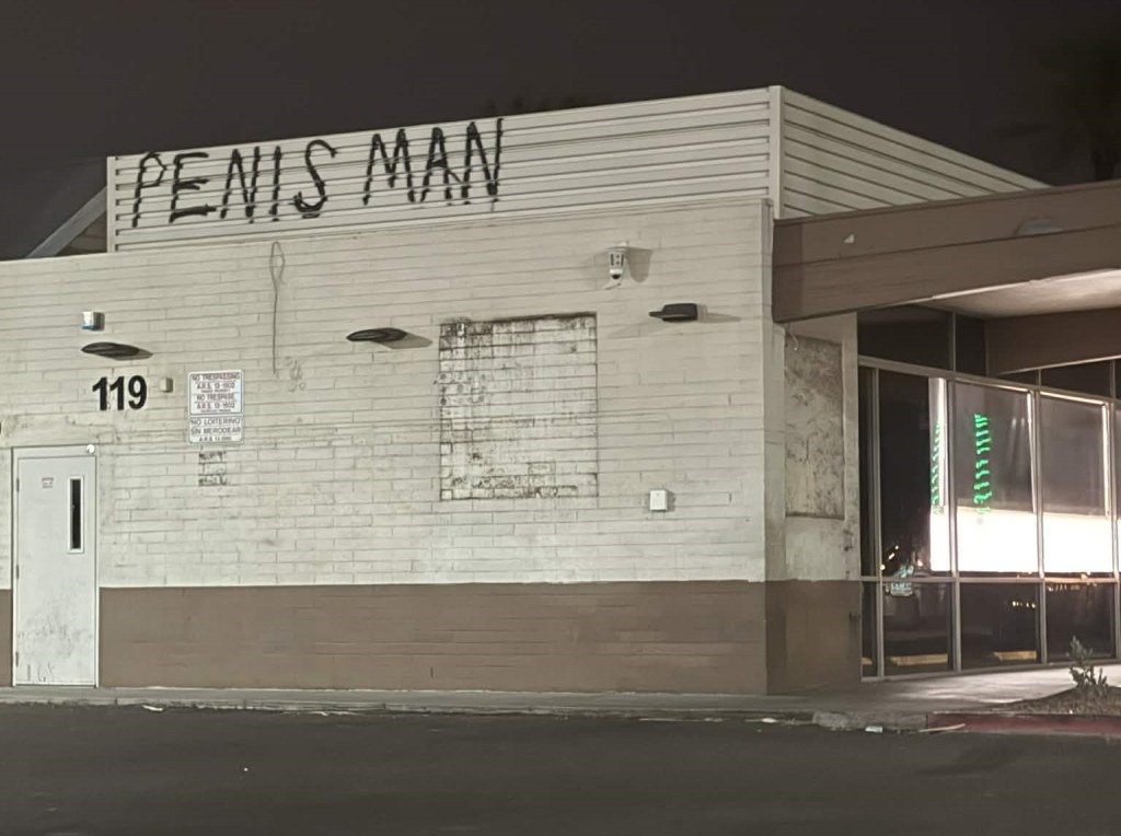A vacant convenience store with the phrase "PENIS MAN" spraypainted on a wall.