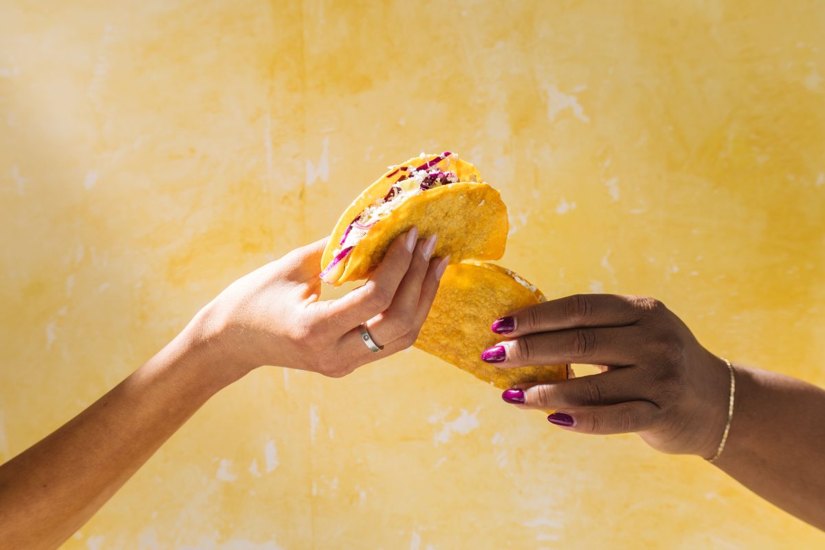 Two hands holding crunchy tacos.