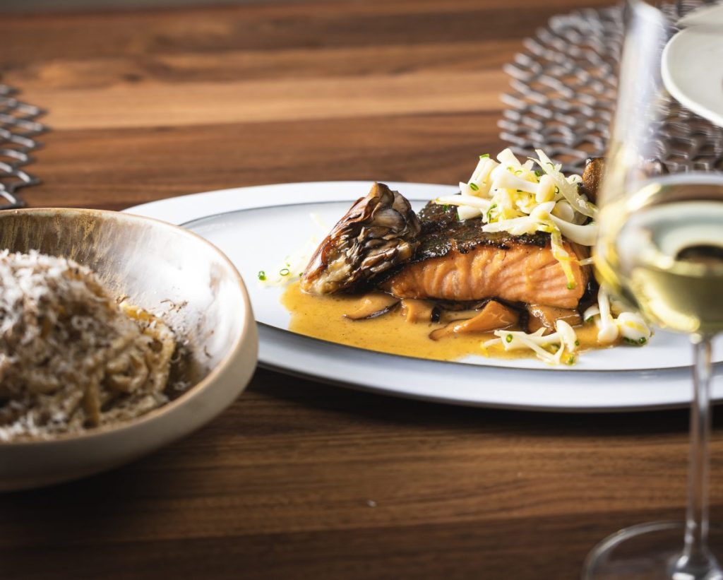 Plates of fish and pasta on a table.