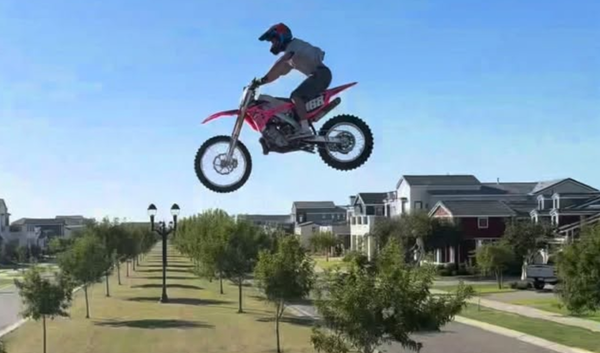 a person on a bmx bike hangs in the air over a neighborhood street