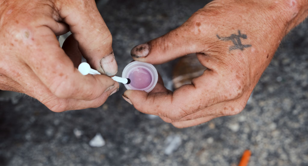 A man's hands prepare to shoot-up a mix of heroin and fentanyl.