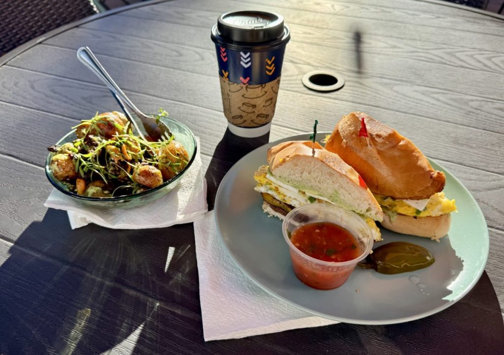 Breakfast plates and a to-go coffee on a patio table.