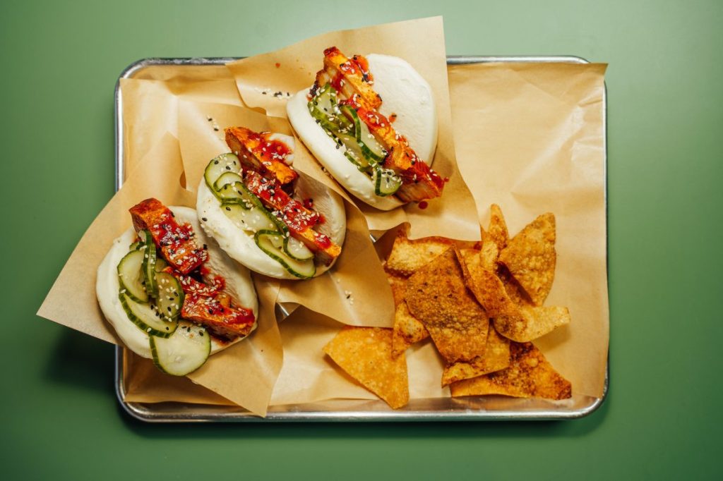 Three Bao buns and chips on a tray.