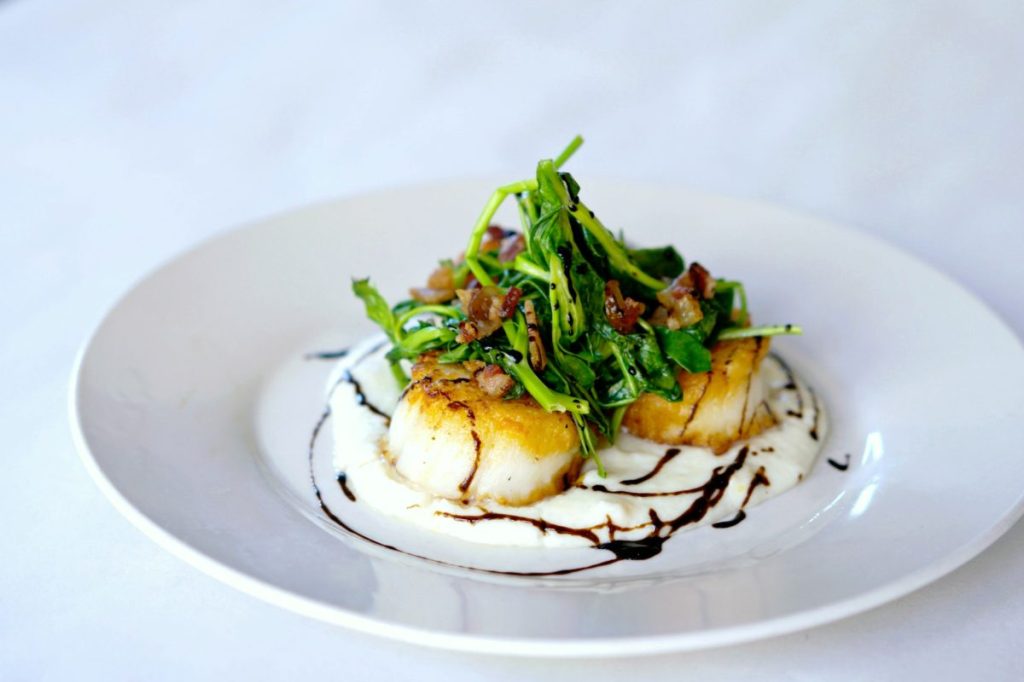 Seared scallops on a bed of grits.