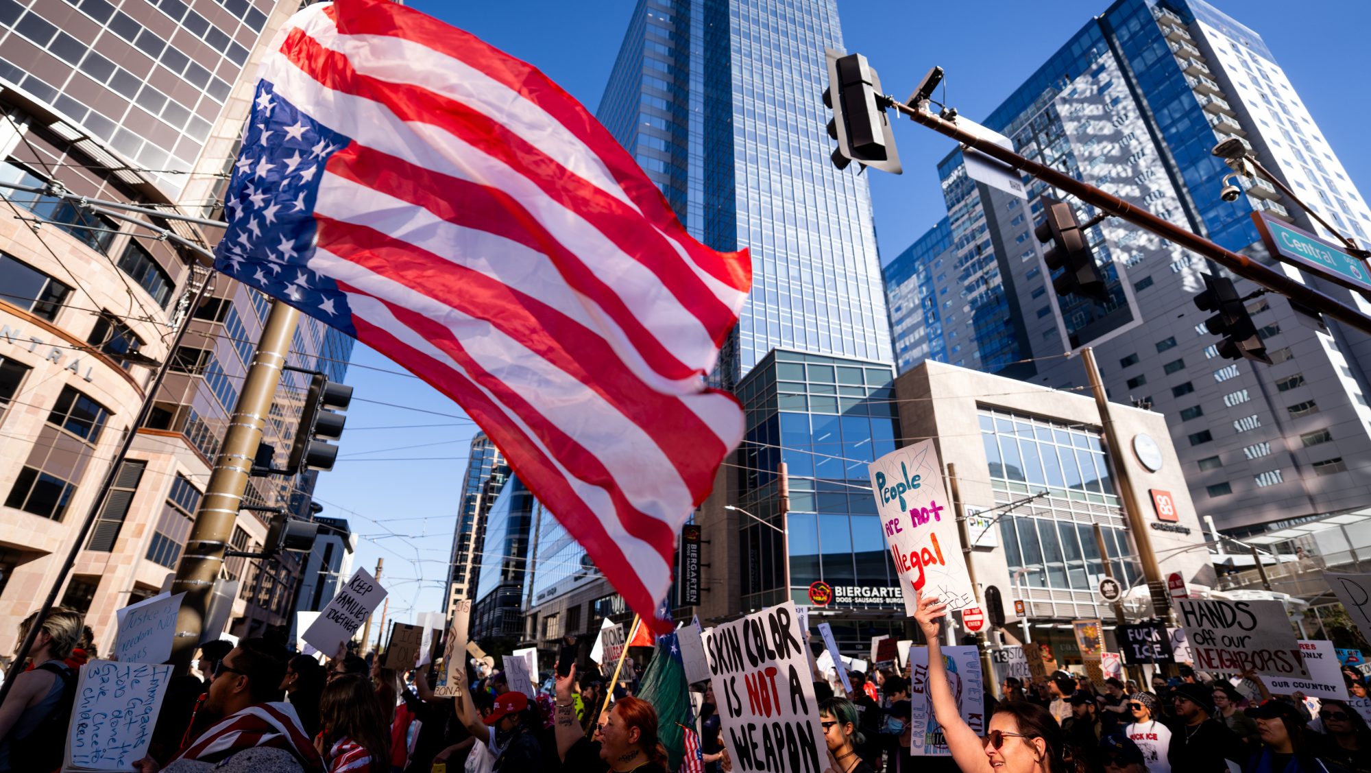 protesters at an anti-ice rally. one holds an upside-down U.S. flag