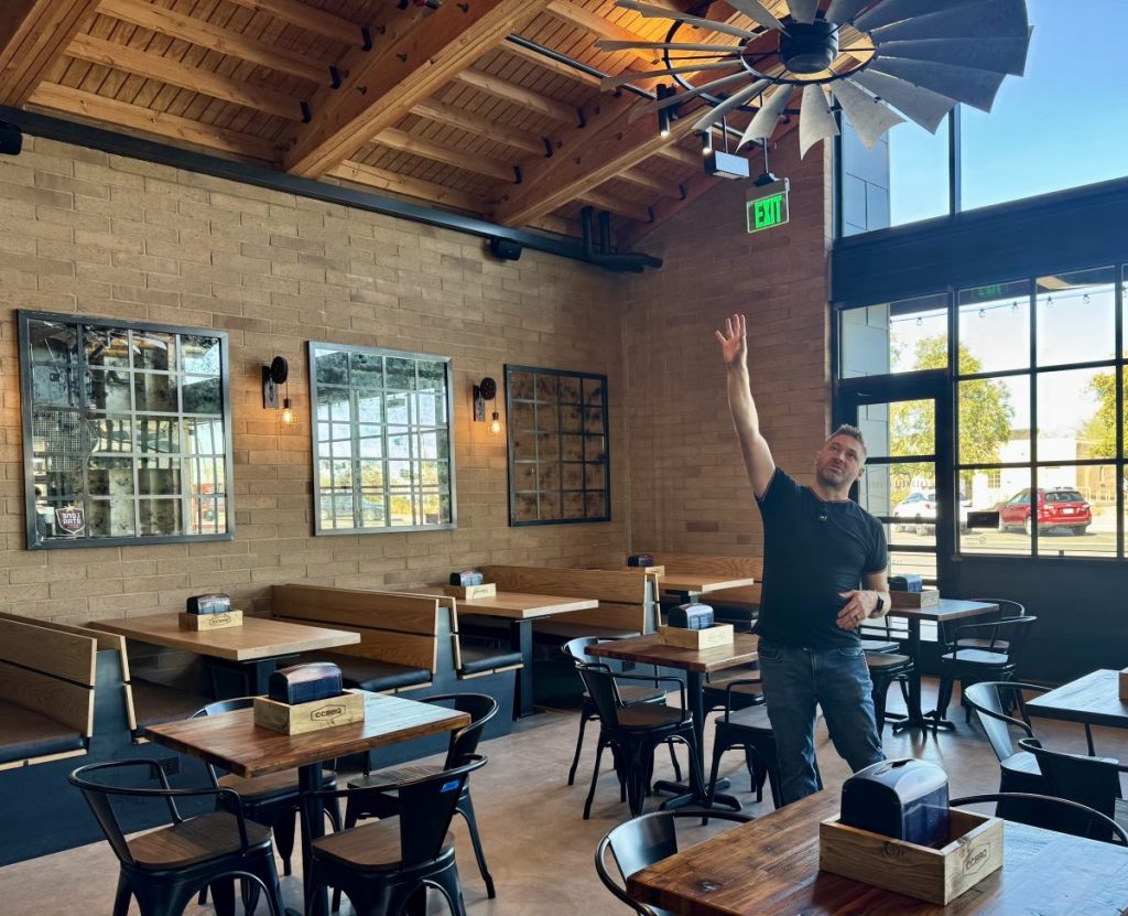 A man pointing to a vaulted ceiling of a restaurant.