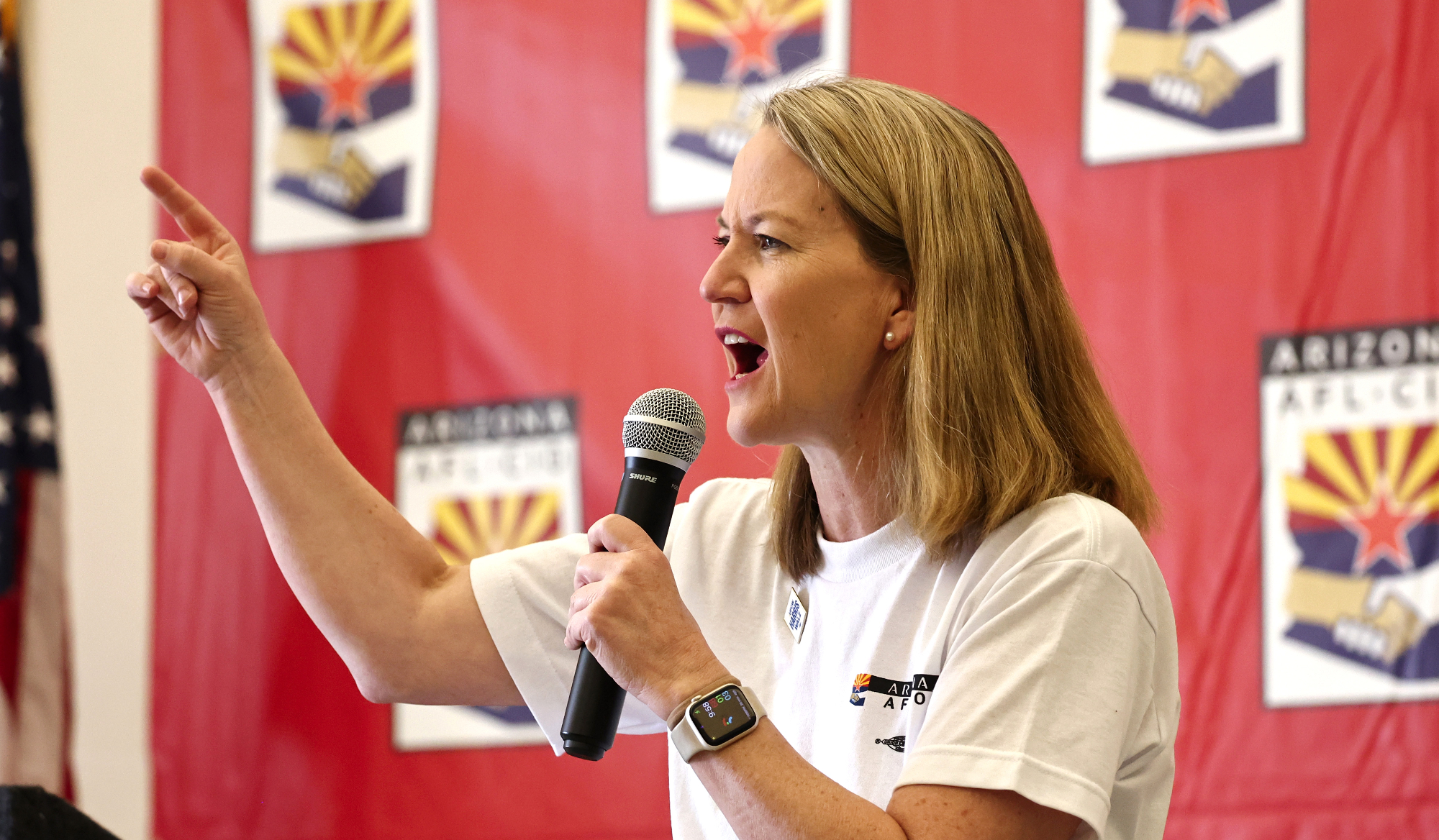 kris mayes points while holding a microphone