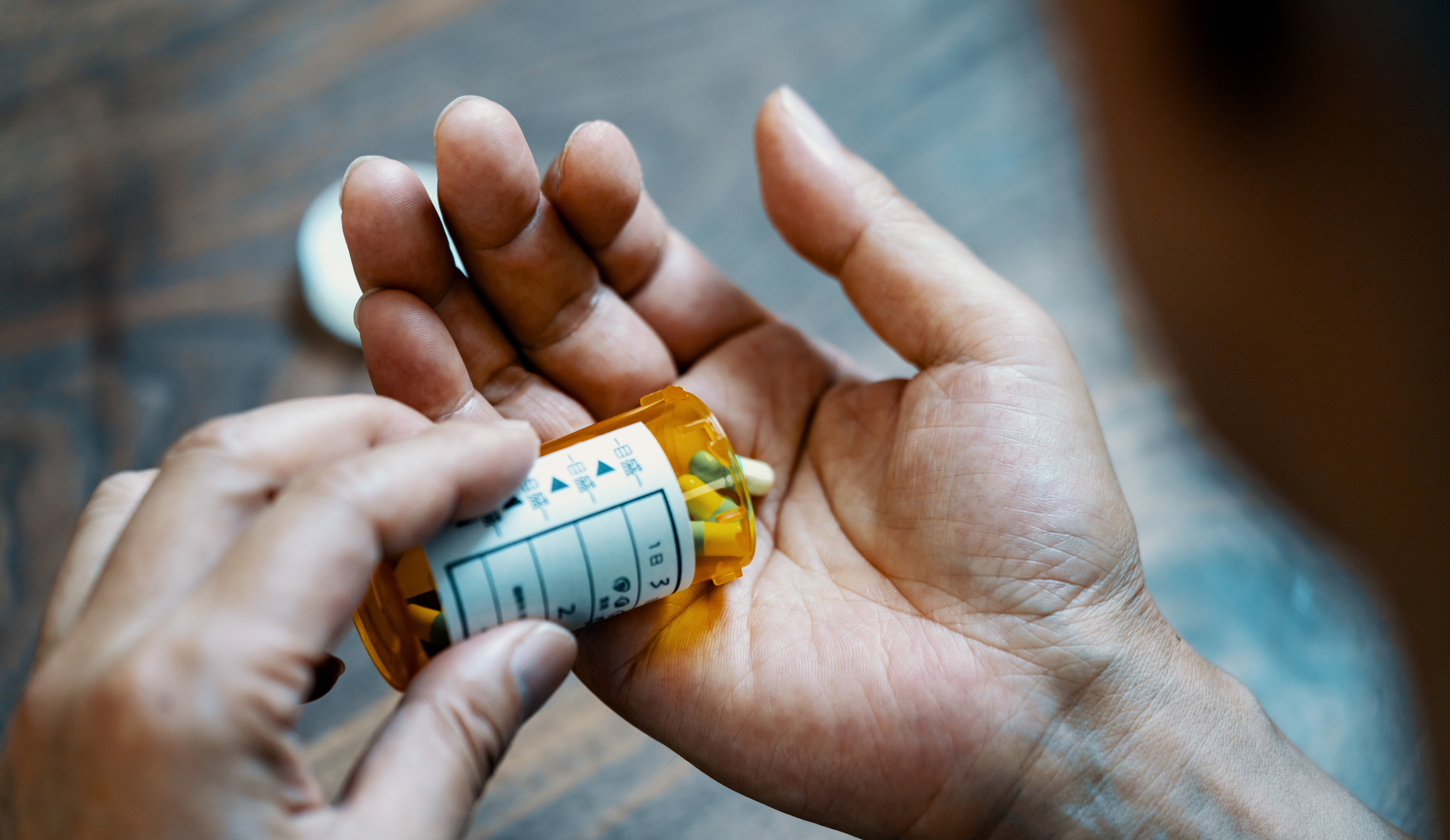 a person pouring pills out of a prescription bottle