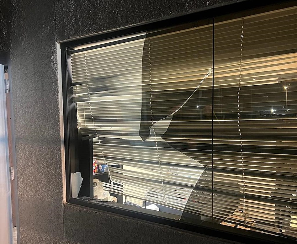 An exterior view of broken window at an office building at night.