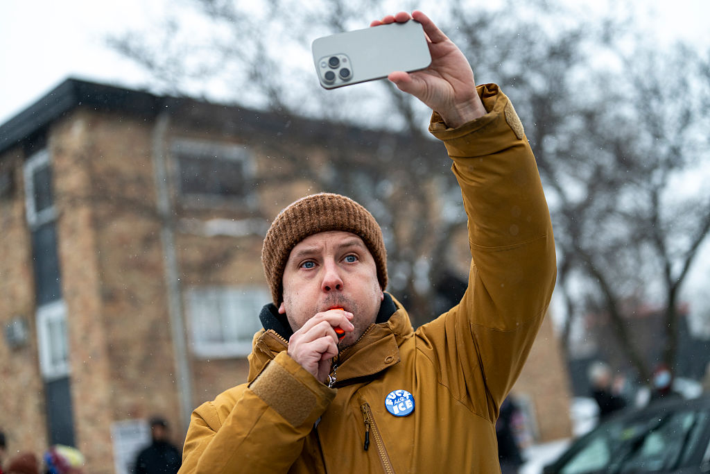 A man blows a whistle at Border Patrol members as they arrest two teenagers after a car crash in Minneapolis.
