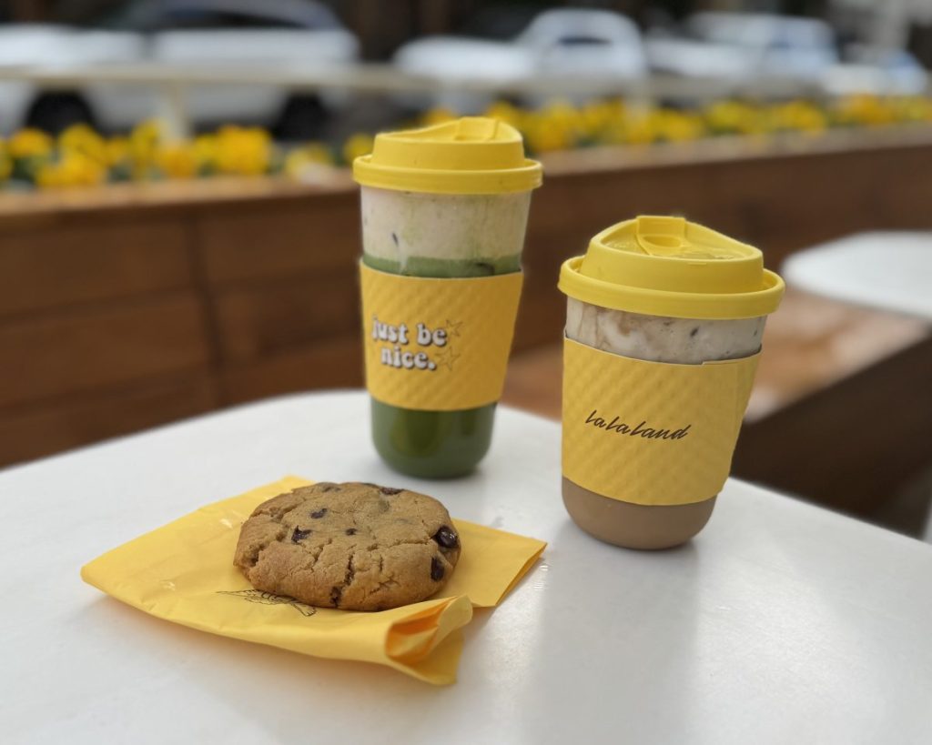 Two cafe drinks and a cookie on a patio table.