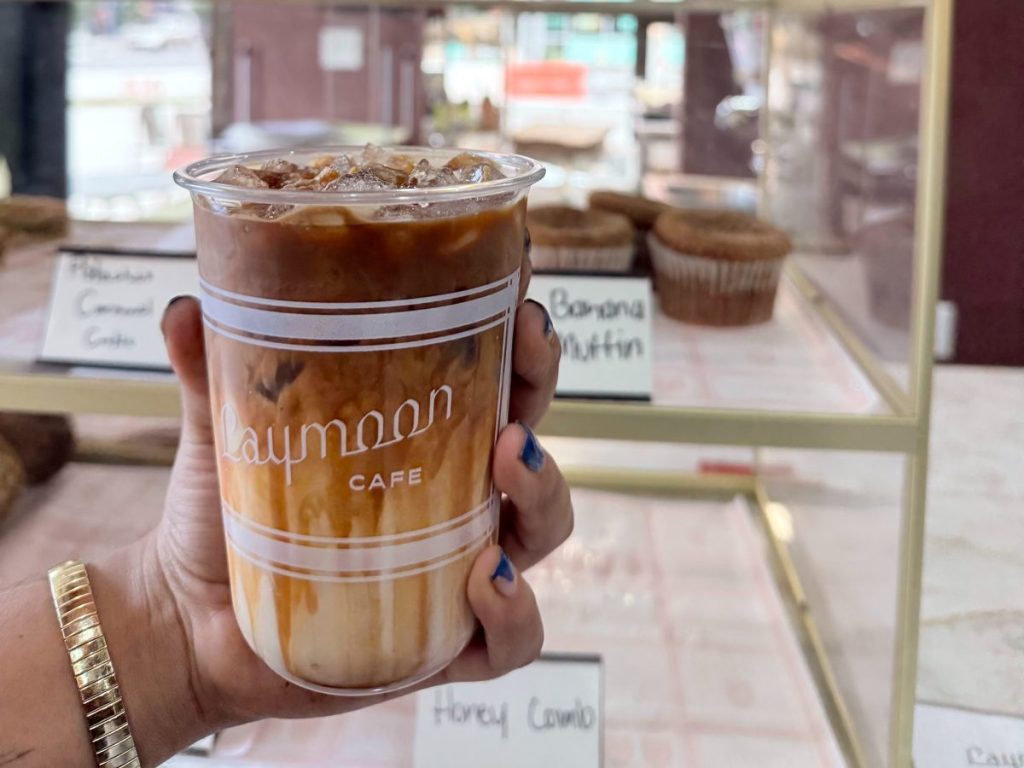 A hand holding an iced latte