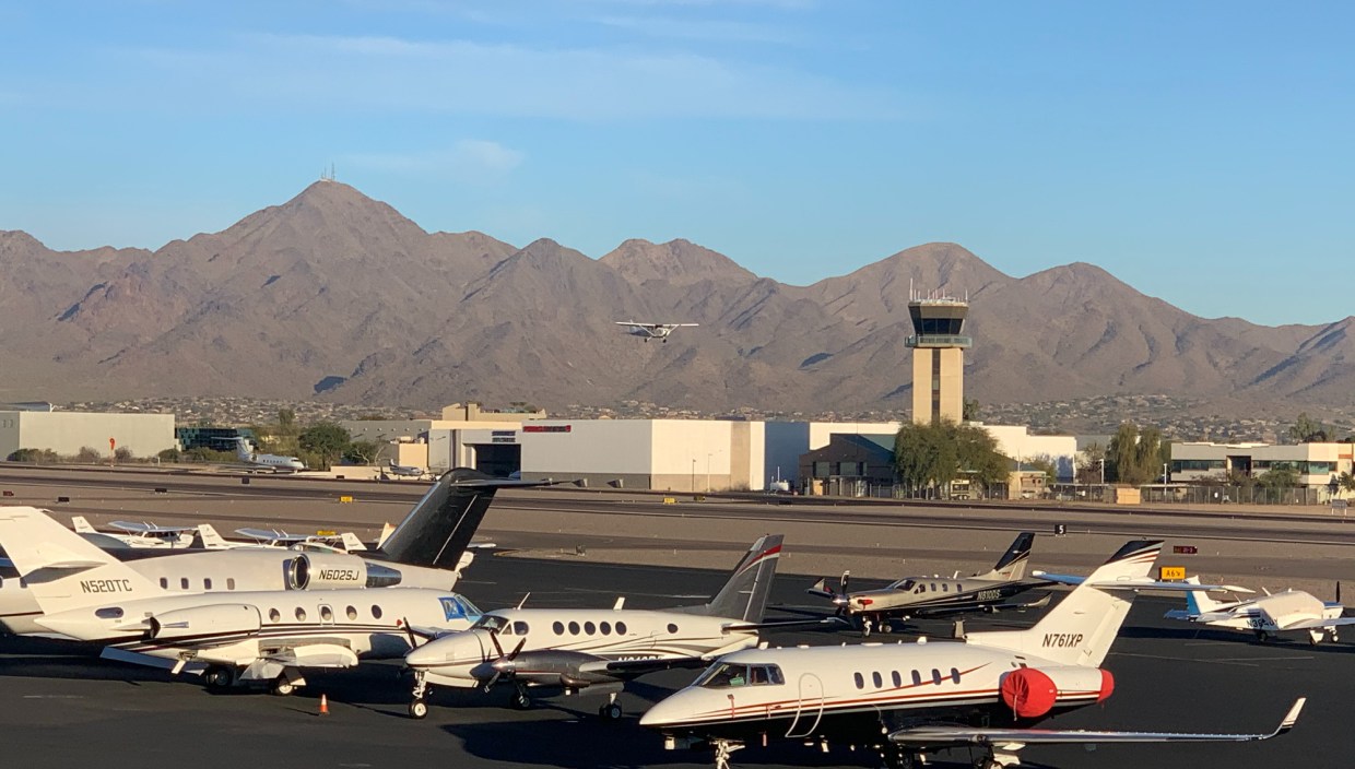 private planes on a runway with mountains in the background