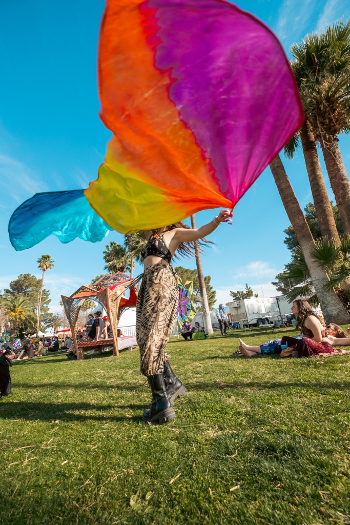 a woman waves colorful fabrics in a park
