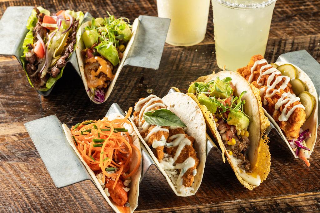 Platters of tacos and margaritas from Velvet Taco on a table.