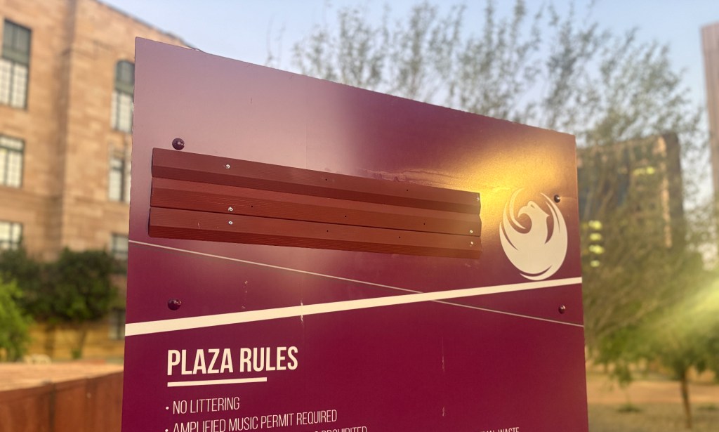 a sign for cesar chavez plaza, with chavez's name covered up by slats hammered onto the sign