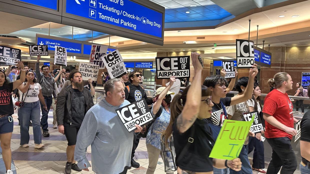 demonstrators wave anti-ice signs while marching through an airport