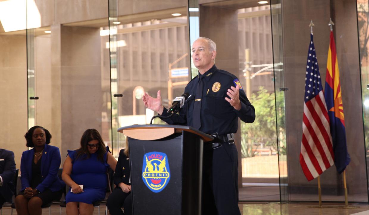 matt giordano speaks at a podium with the phoenix police logo