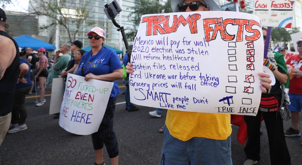 a protester holds a sign that says "so fucked up even introverts are here"