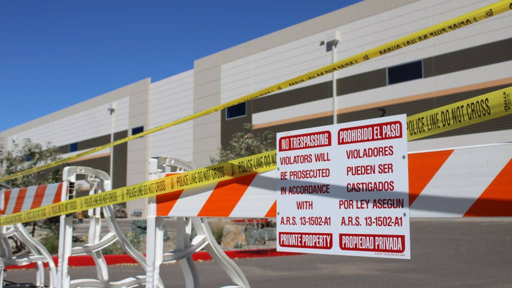 caution tape and warning signs bar people from approaching a warehouse purchased in surprise to become an ICE detention center.