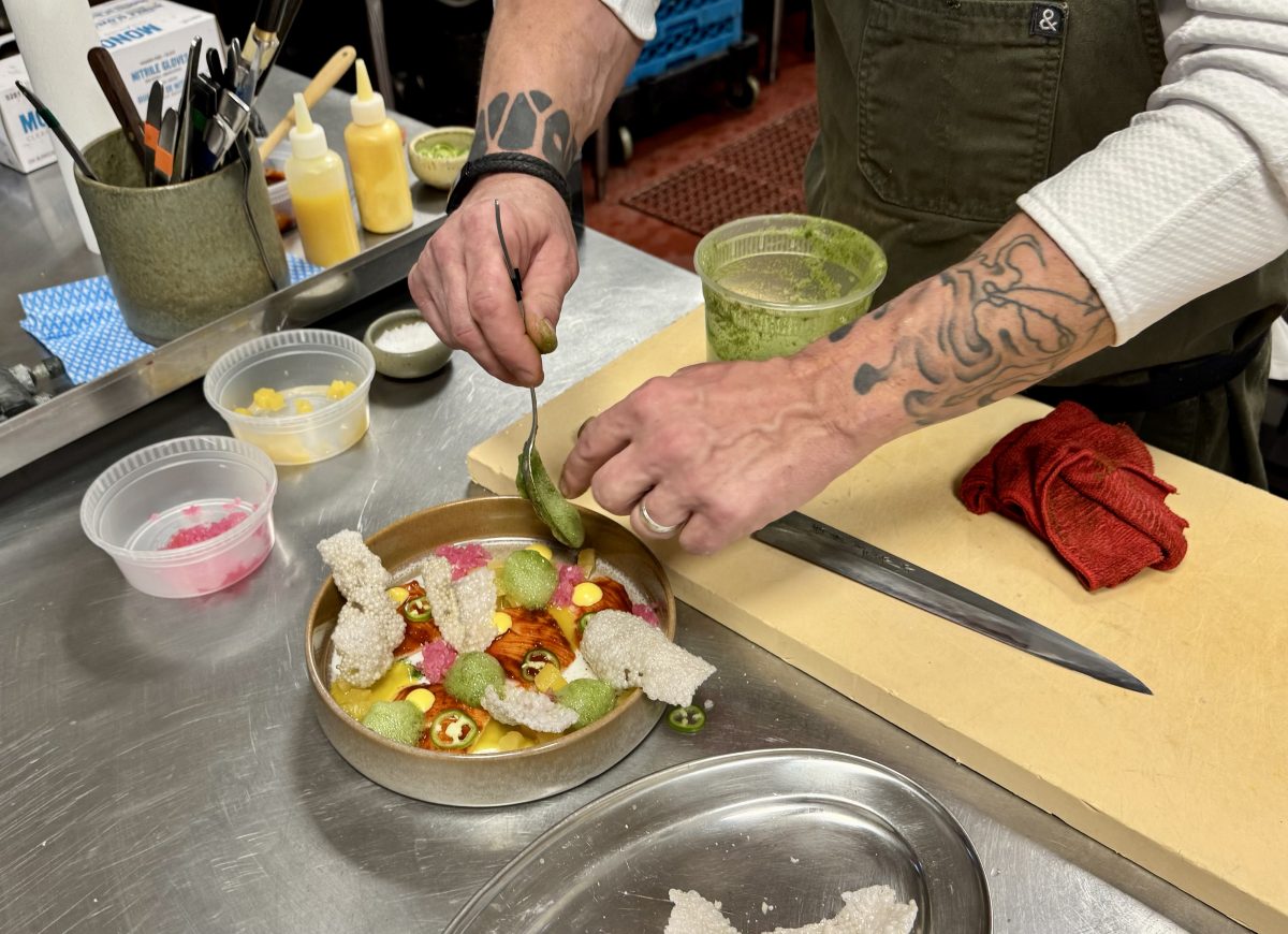 Chef Steven "Chops" Smith delicately spoons cilantro foam onto a plate of crudo.