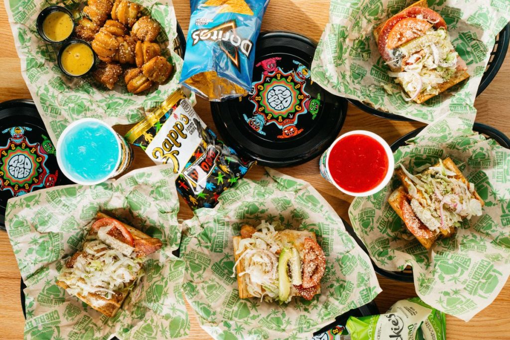 A table full of sandwiches, chips and drinks from Cheba Hut.