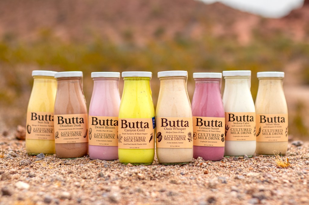 Eight milk bottles filled with colorful drinks by Butta, a cultured milk drink.
