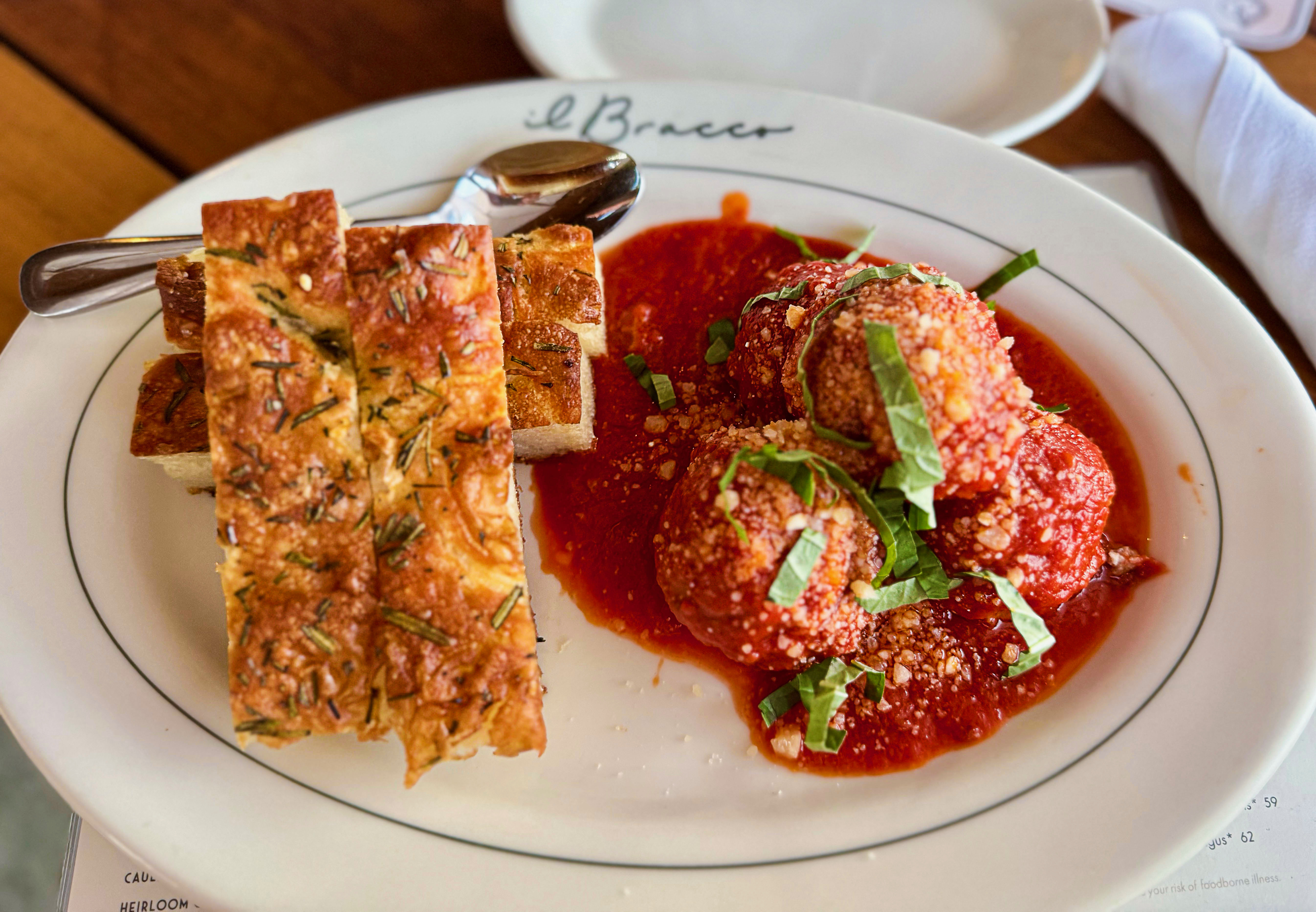 A plate with batons of focaccia bread and meatballs.