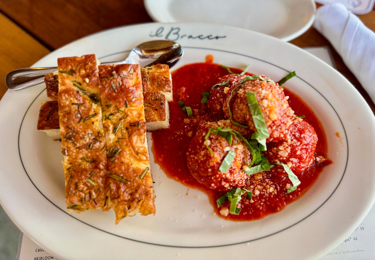 A plate with batons of focaccia bread and meatballs.