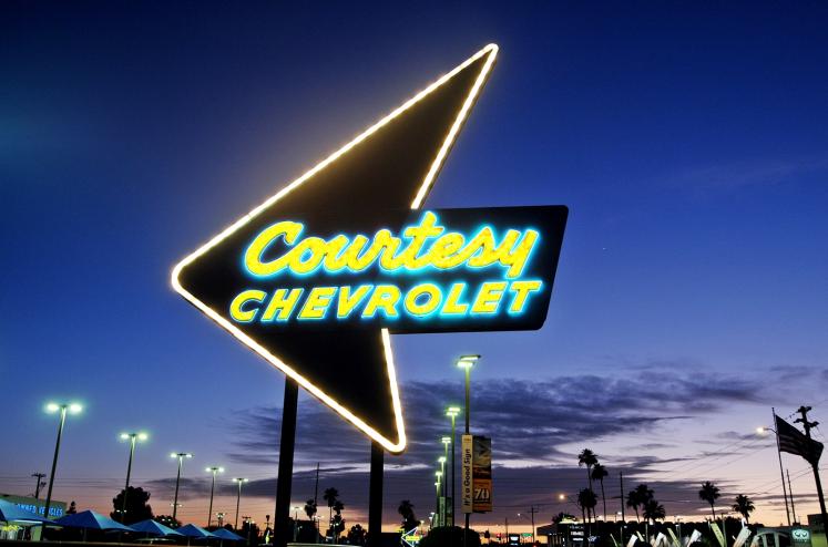The vintage neon Courtesy Chevrolet sign glows against the twilight sky along Camelback Road in Phoenix.