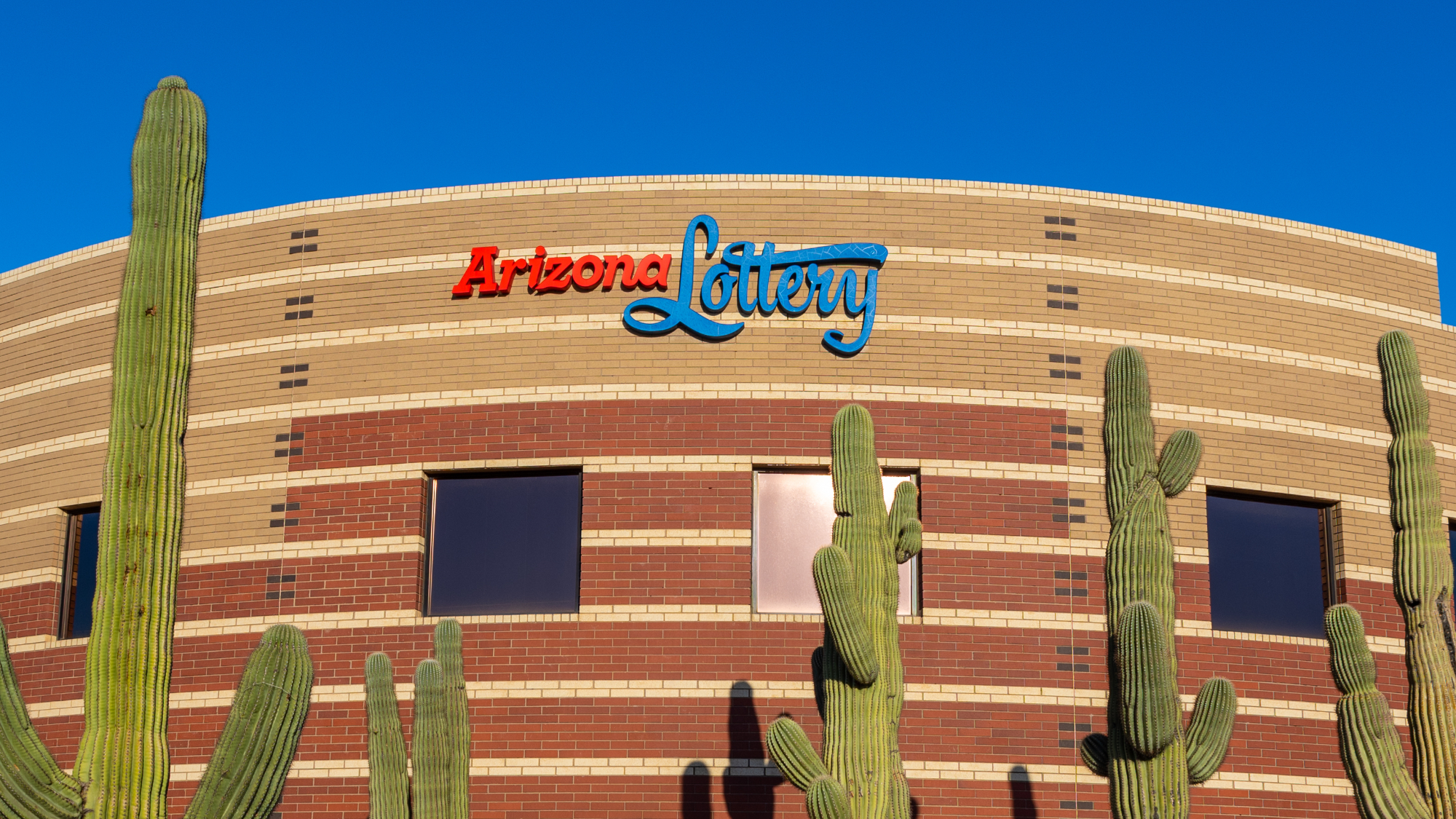 a building with the arizona lottery logo on it, with saguaro cacti in front
