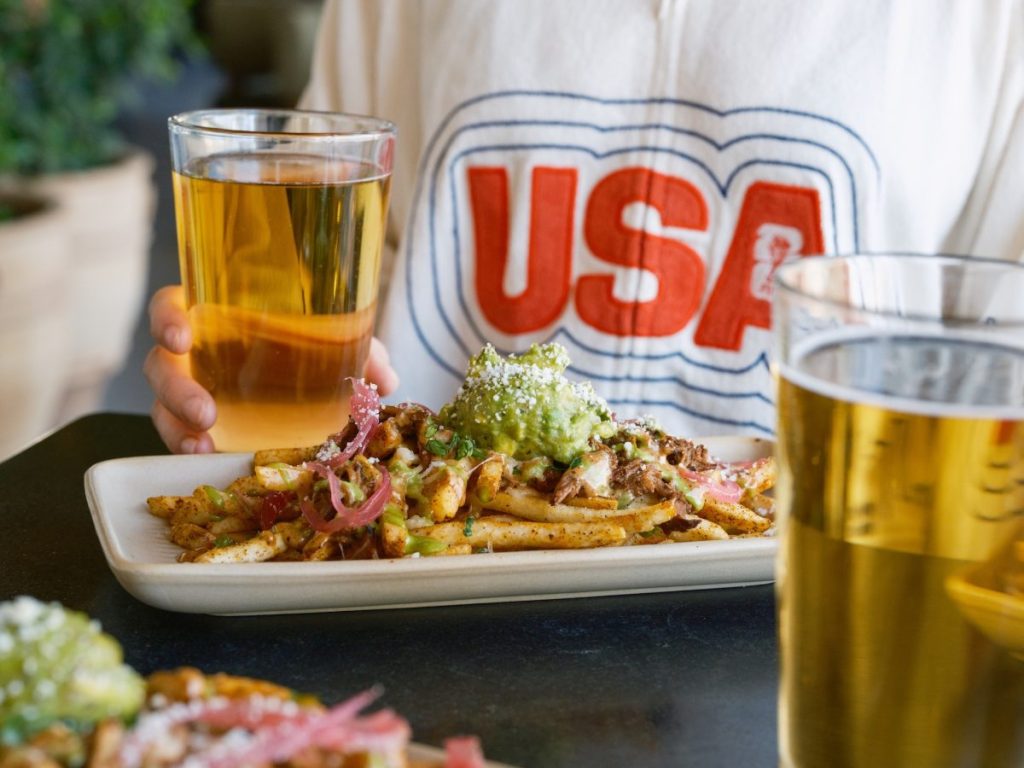 A U.S. soccer fan with Blanco Cocina + Cantina's loaded fries and a pint.