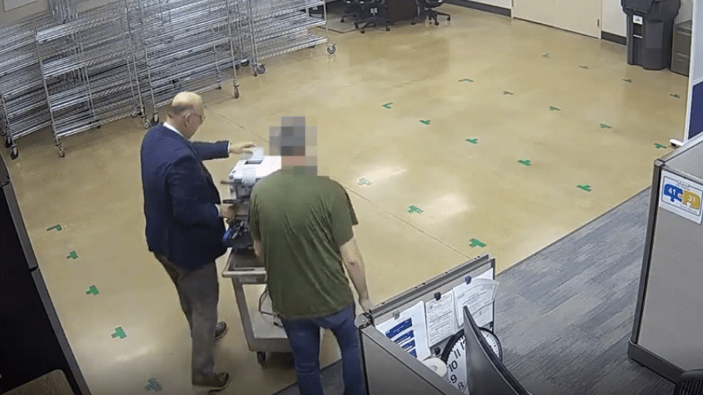 a security cam still showing bryan colby and another person wheeling a scanner through a room