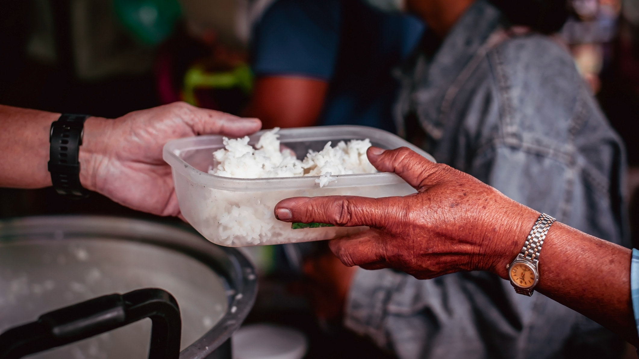 one person hands a container of food to someone else