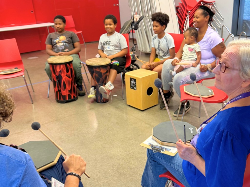 Participants play hand drums during a community drum circle at Harmon Library as part of Make Music Day Phoenix.