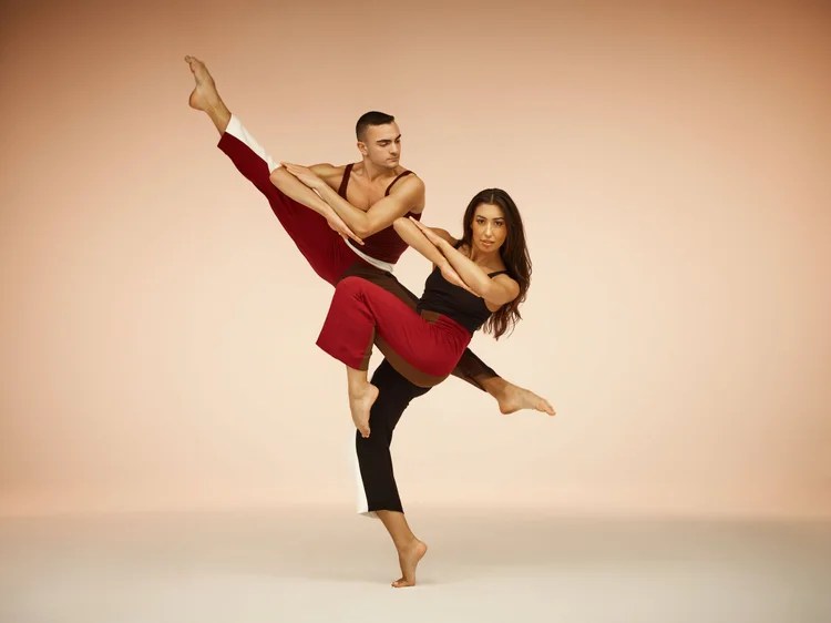 Two Parsons Dance performers strike an athletic pose during a promotional photo for the contemporary dance company's 2026-27 tour.