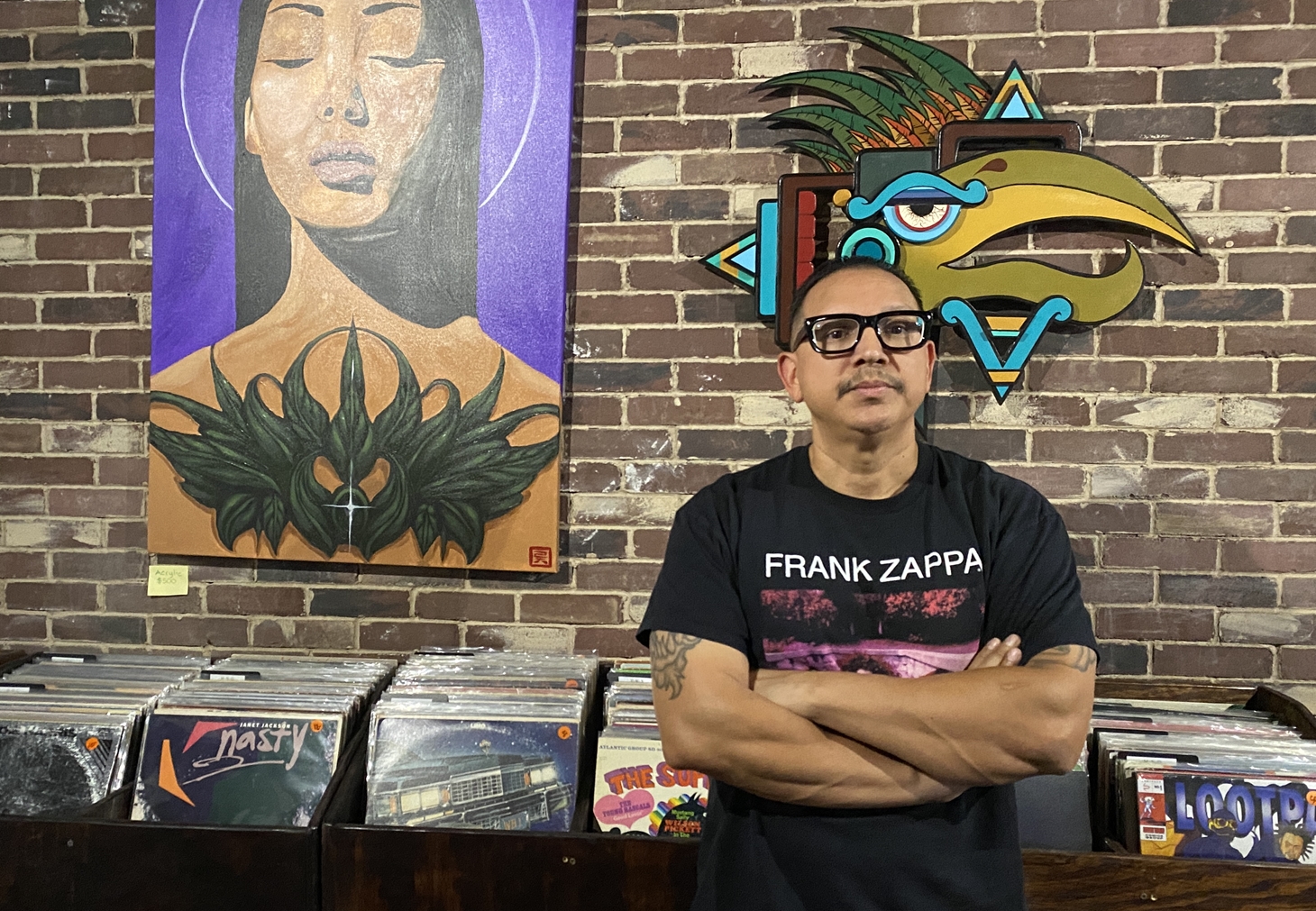 The Record Gallery owner Damian Amoros stands inside his new Phoenix record store, which features vinyl bins and colorful local artwork.